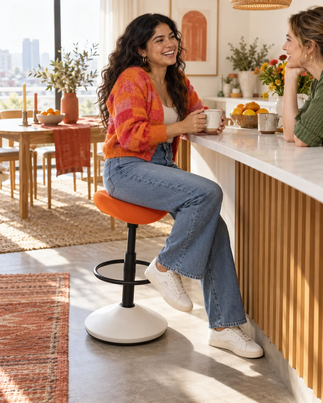 Woman on an orange saddle wobble stool chatting with a friend in her kitchen