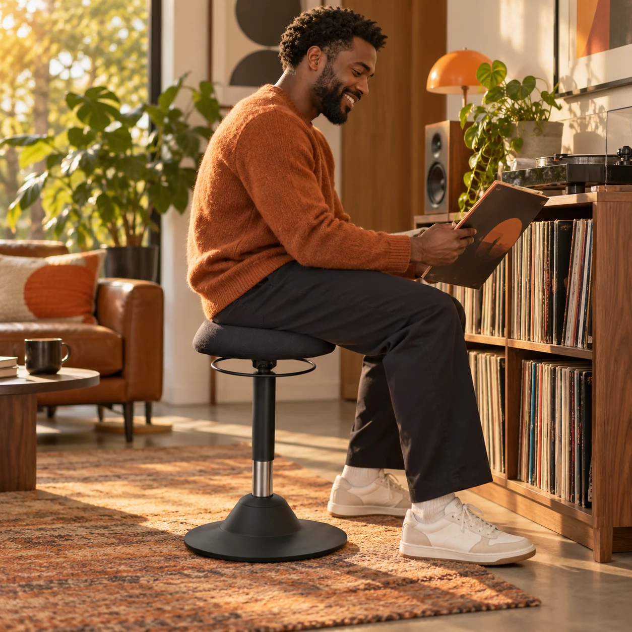 Man enjoying music while seated on the black Orbit stool